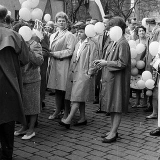 Group of people holding balloons in a public space.