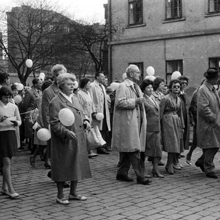 Group of people march with signs and balloons.