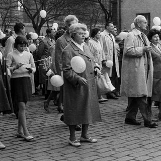 Group of people march with signs and balloons.