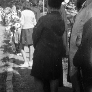 Medical personnel walk along a road with onlookers.