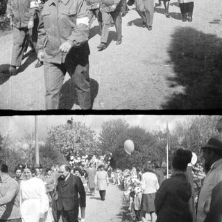 Medical personnel walk along a road with onlookers.