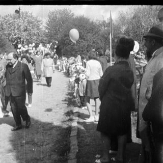 Medical personnel walk along a road with onlookers.