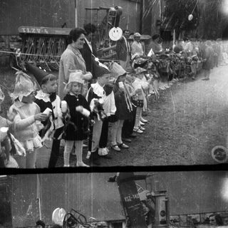 Children stand near a tractor at an event.