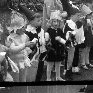 Children stand near a tractor at an event.