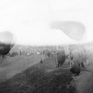 People watch airships or hot air balloons in a field.