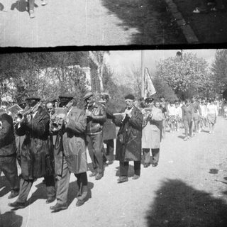 Parade with marching band and onlookers in a street.