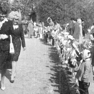 Children march past a vehicle, possibly in a parade.