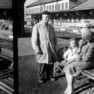 Woman, child, and man near a train station.