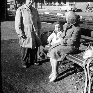 Woman, child, and man near a train station.