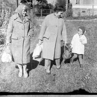 Here's a brief summary of the image: Three figures walk along a grassy path.