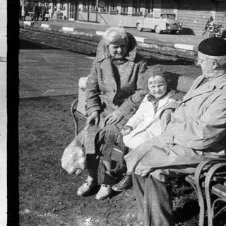 Here's a brief summary of the image: Black and white photo: toy soldiers, elderly couple on bench.