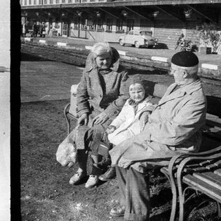 Here's a brief summary of the image: Black and white photo: toy soldiers, elderly couple on bench.