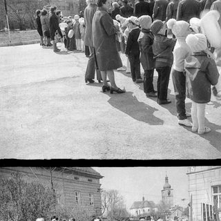 Group of people walk along a street, likely in a procession.
