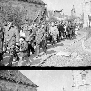 Parade of people marching along a street in a town.