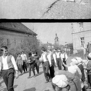 Here's a brief summary of the image: Marching band parades along a road, town in background.