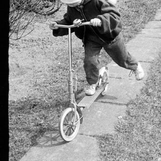 Two children play outdoors on a concrete path.