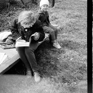 Two children play outdoors on a concrete path.
