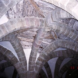 Arched stone ceiling with intricate ribbing and wooden beams.