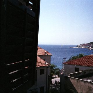 Coastal town rooftops overlook a bay with sailboats.