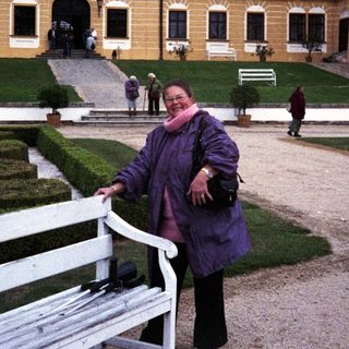 Woman poses in front of an ornate, yellow palace.