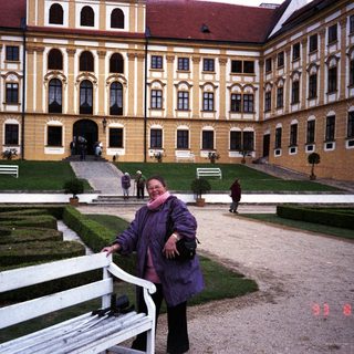 Woman poses in front of an ornate, yellow palace.