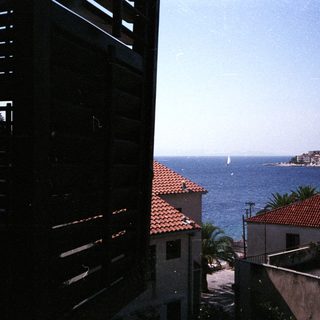 Coastal town view through shutters with boats on the sea.