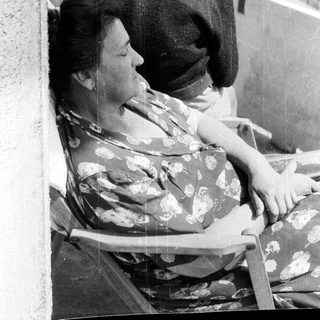 Here's a brief summary of the image: Woman resting on a chair, man standing nearby.