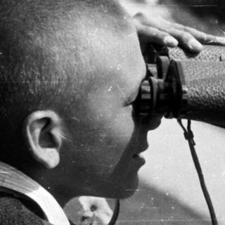 A young boy looks through binoculars, possibly at a view.