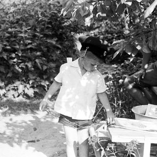 Boy in hat stands near a table outdoors.