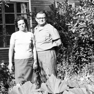 Couple stands in front of a modest home.