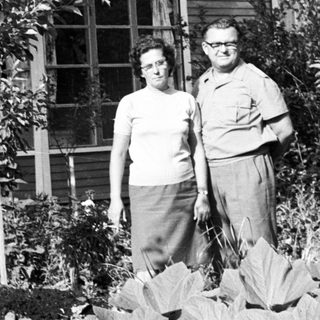 Couple stands in front of a modest home.