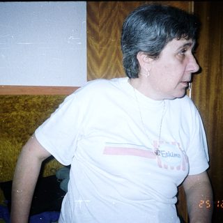Here's a brief summary of the image: Woman in a t-shirt stands in a room.