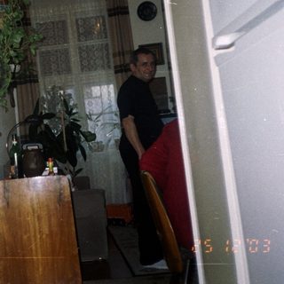 Man stands in kitchen, viewed through doorway with decor.