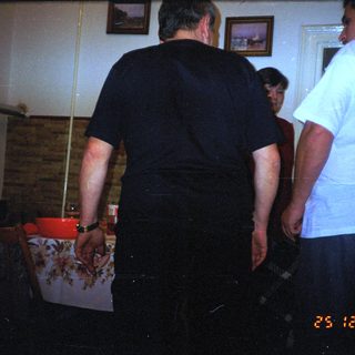 Two men stand near a pool table in a dimly lit room.
