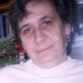 Woman holding wine near a decorated Christmas tree.