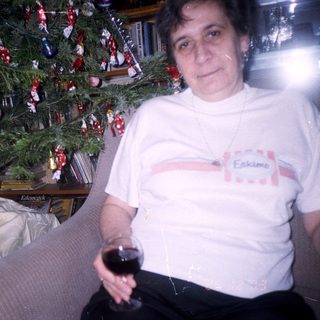 Woman holding wine near a decorated Christmas tree.