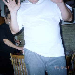 Man in white shirt stands near person smoking indoors.