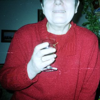 Person holds a glass, room with plants and a clock.