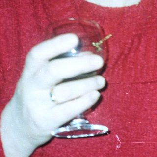 Person holds a glass, room with plants and a clock.