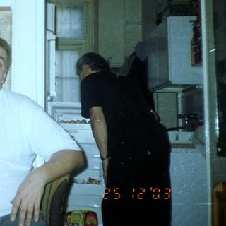 Man sits with camera, seemingly in a kitchen setting.