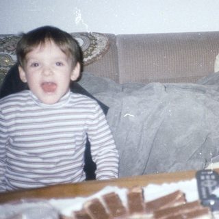 Boy makes silly face; woman relaxes on a sofa.
