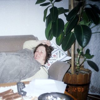 Boy makes silly face; woman relaxes on a sofa.