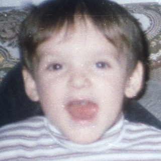Boy makes silly face; woman relaxes on a sofa.