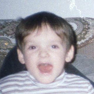 Boy makes silly face; woman relaxes on a sofa.