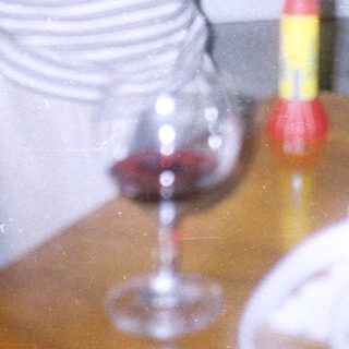 Girl stands near table with wine glass and food.