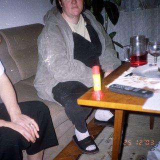 Two people seated on a couch, drinks and food nearby.