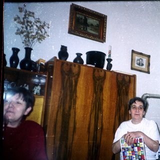 Two people stand in a room with vases and decor.