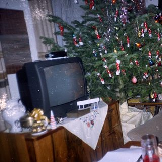Vintage living room with a decorated Christmas tree and television.