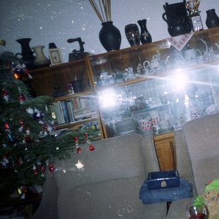 Man sits near a Christmas tree in a room.