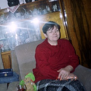 Man sits near a Christmas tree in a room.